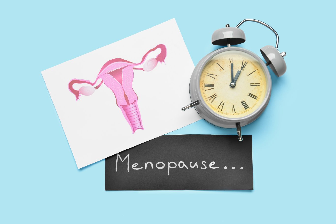 Menopauseと書かれた紙と時計と青い背景
